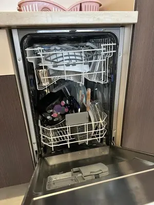 an open dishwasher filled with dishes and other items at Thousand Roses in Podgorica