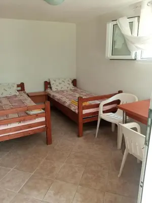 a room with two beds and a table and a table at гостевой дом Polina2 in Gornji Sušanj