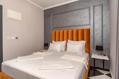 a bedroom with a large bed with an orange headboard at Baba's Hotel & Spa in Dobra Voda