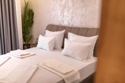 a bed with white sheets and white pillows at Baba's Hotel & Spa in Dobra Voda