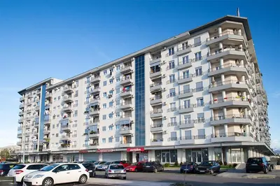a large apartment building with cars parked in a parking lot at Apartman Tanjuška in Podgorica