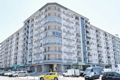 a large building with cars parked in a parking lot at Apartman Tanjuška in Podgorica