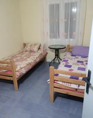 a room with two beds and a table in it at Гостевой дом Polina in Gornji Sušanj