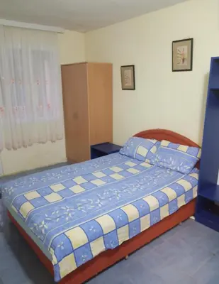 a bedroom with a bed with a blue and white blanket at Гостевой дом Polina in Gornji Sušanj