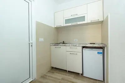 a small kitchen with white cabinets and a refrigerator at DERON Apartments in Ulcinj