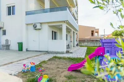 a house with a playground with toys in the yard at DERON Apartments in Ulcinj