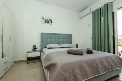 a bedroom with a large bed with a green headboard at DERON Apartments in Ulcinj