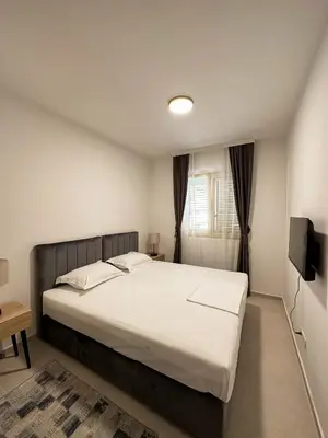 a bedroom with a large bed and a television at Vertmont Apartments in Sveti Stefan
